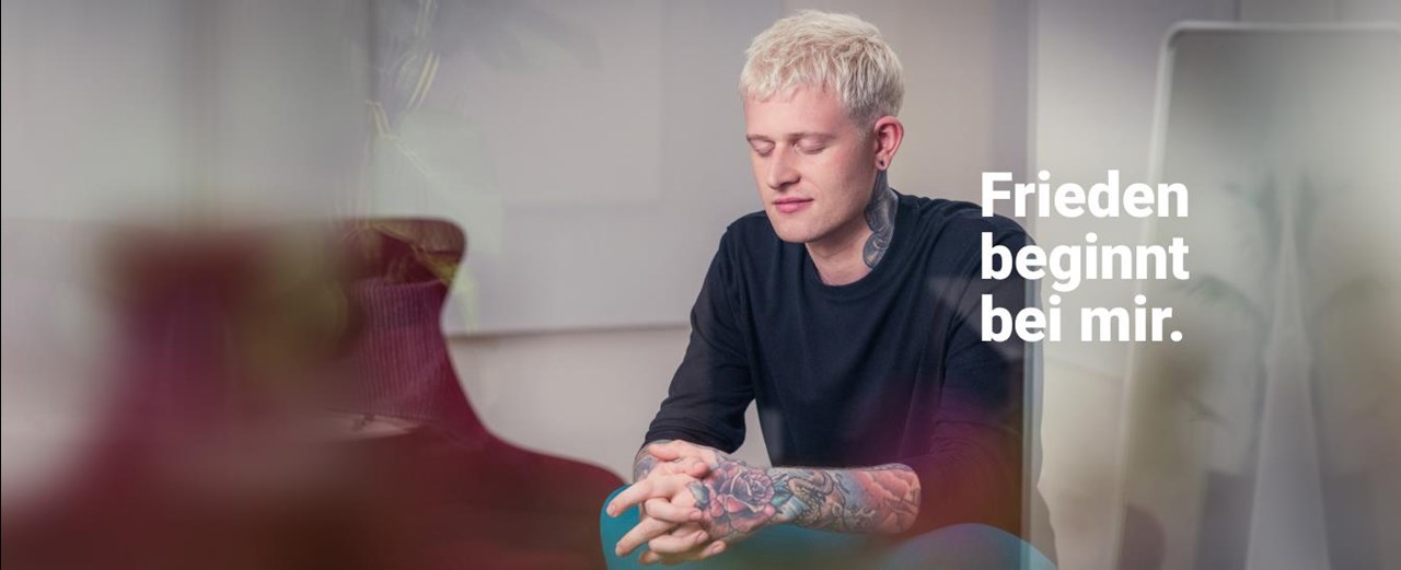 Ein junger Mann mit kurzen blondierten Haaren mit der Aufschrift "Friede beginnt bei mir."