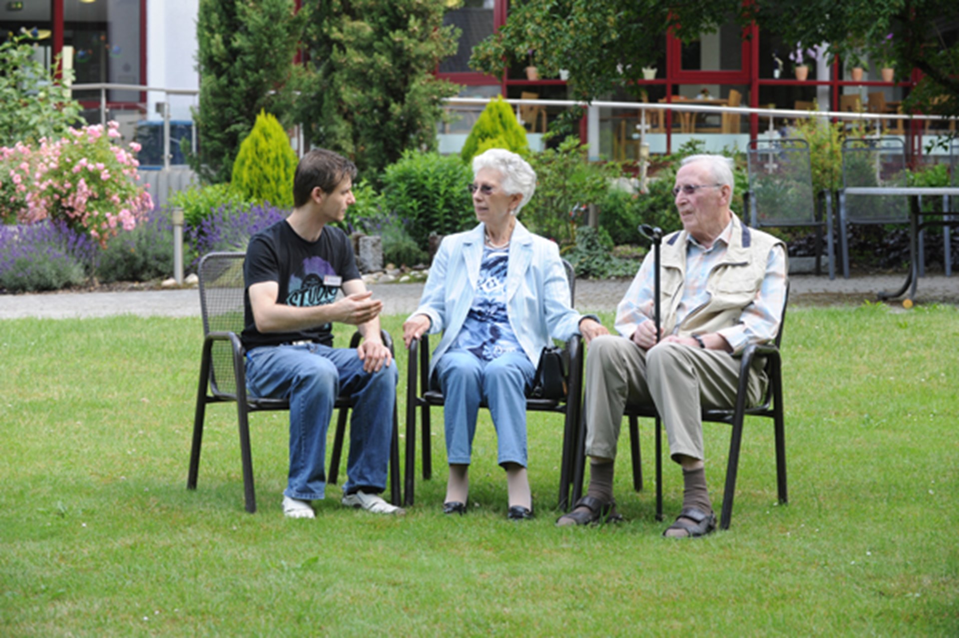 altes Ehepaar mit Pfleger im Garten